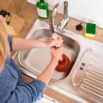 girl unclogs a clogged sink in the kitchen